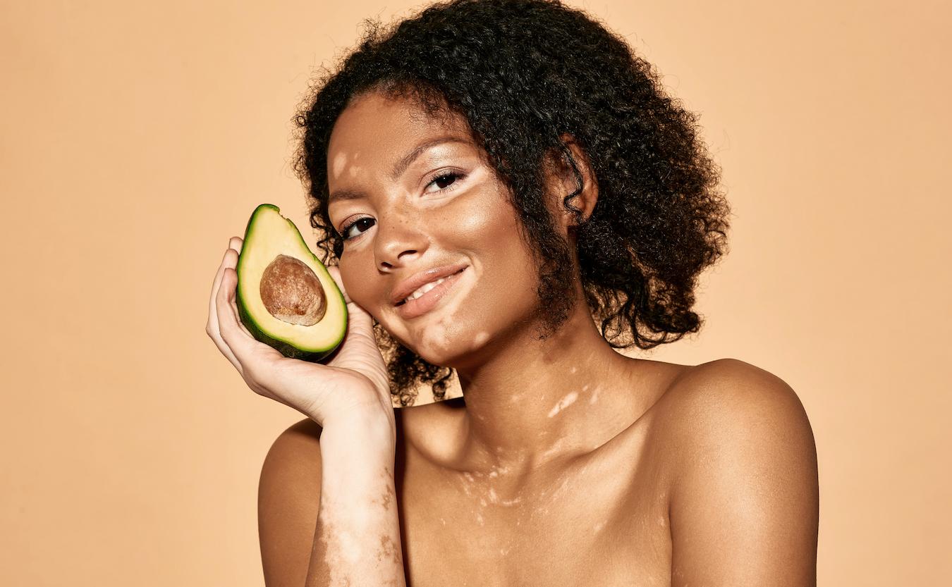 Woman holding an avocado to her face